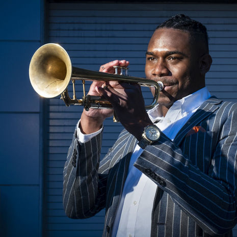 Image of Fareed Simpson-Hankins playing trumpet outside. 
