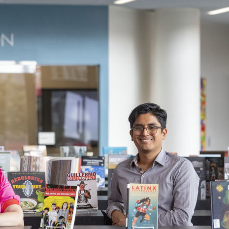 Professors Christina Baker, César Cabezas and Augusto Lorenzino standing in front of books on display in Charles Library for Hispanic Heritage Month