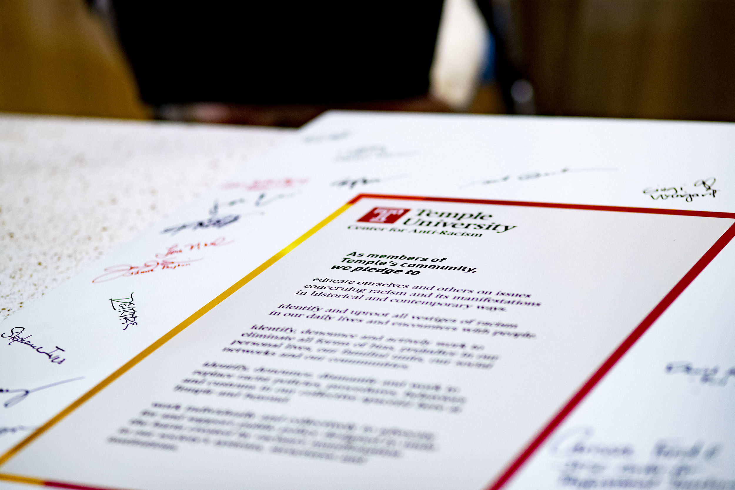 A document surrounded by written signatures sits on a table.