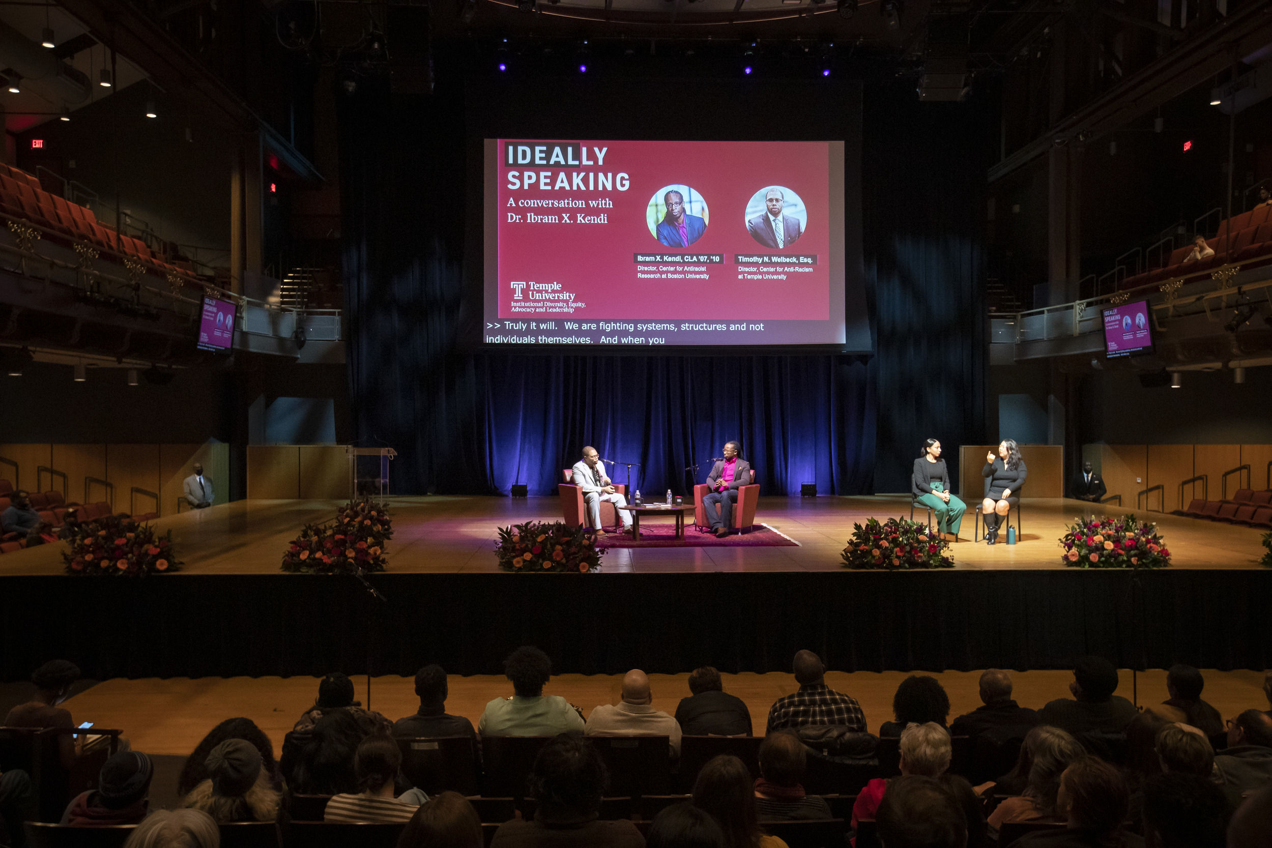 The stage at the Temple Performing Arts Center shown with two seated men in the middle and two women seated towards the side of the stage.